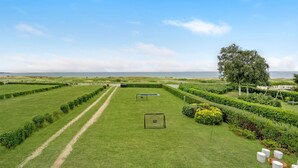 A well-maintained lawn with pathways, a seating area, and a view of the sea. - Lovely home in Haderslev (Haderslev)