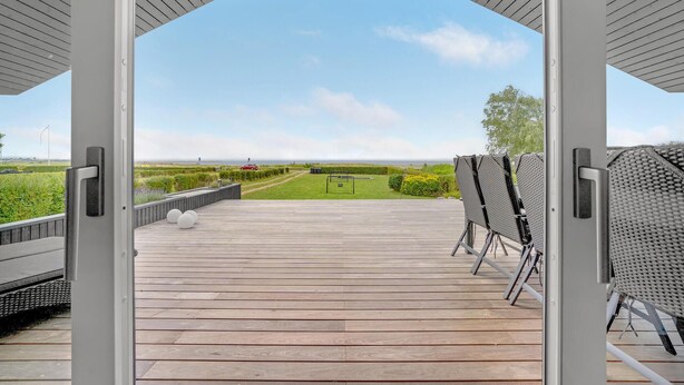 An open wooden deck with a view of a grassy field and a distant road. - Lovely home in Haderslev (Haderslev)