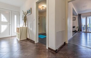 Stunning hallway with a warm and inviting atmosphere, featuring a combination of dark and light brown tiles and a glass door leading to a balcony with outdoor views.