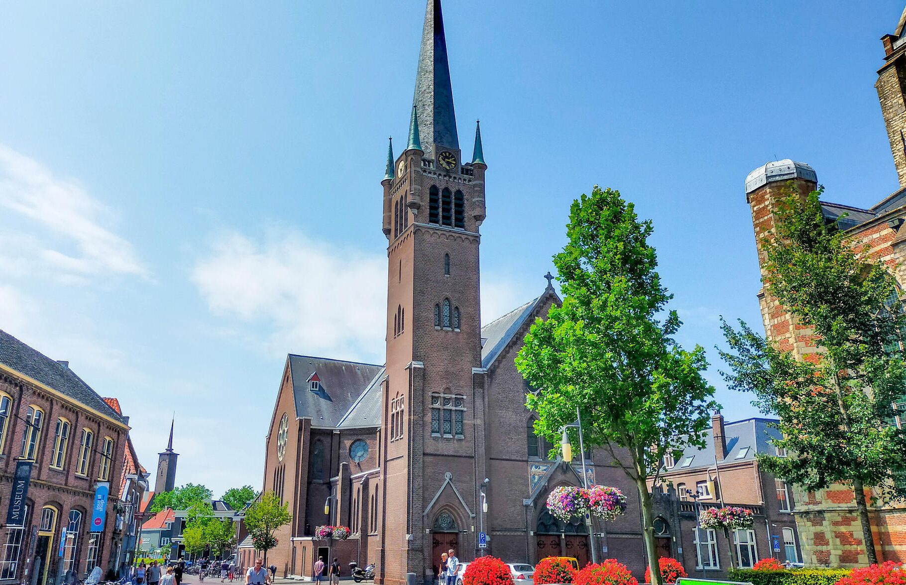 A historic church with a tall spire, a prominent clock tower, and a large stained glass window.