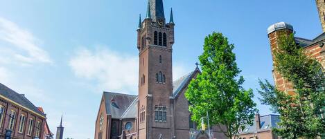 A historic church with a tall spire, a prominent clock tower, and a large stained glass window.