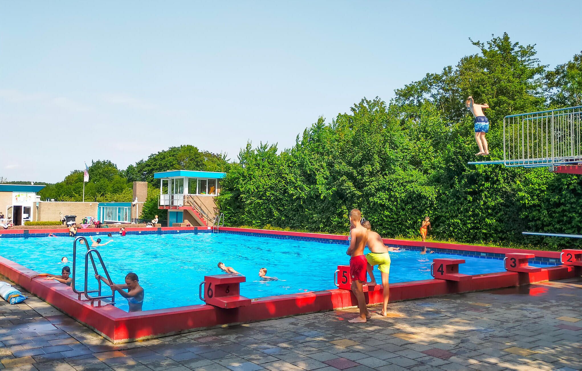 Una piscina con trampolín y torre de salvavidas.