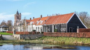 Un bâtiment historique avec un toit recouvert de tuiles rouges, une tour et un canal en contrebas.