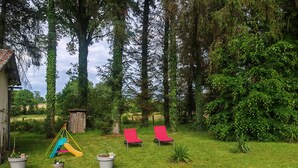 A grassy outdoor area with a slide, two red chairs, and potted plants. - Discovering the Périgord, Haute-Vienne and Corrèze regions  (Ladignac-le-Long)