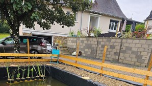 A small pond with water lilies, surrounded by a wooden fence and a stone wall. - Discovering the Périgord, Haute-Vienne and Corrèze regions  (Ladignac-le-Long)