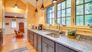 Una cucina con pareti in legno, piani in granito, un lavello e luci a sospensione.