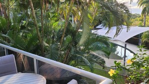 A balcony with a view of lush greenery and a white canopy structure. - Luxury Haven, Pool, Internet, HDTV, Gym (Palm Cove)