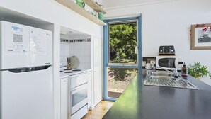 Eine moderne Küche mit weißen Schränken, einem eingebauten Backofen, einer Mikrowelle und einem Toaster. Ein Fenster bietet Blick auf Grünfläche.