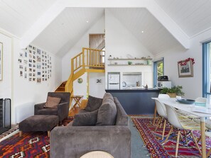 Ein geräumiger Wohnbereich mit hoher Decke, einer Treppe, einer Küche und einem Essbereich.