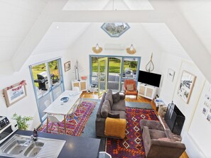 Ein großzügiger Loft mit hohen Decken, einem Essbereich mit Tisch und Stühlen, einer Sofagarnitur, einem Kamin und großen Fenstern mit Blick ins Freie.
