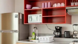 Una cucina compatta con frigorifero, microonde e macchina da caffè sul piano di lavoro.