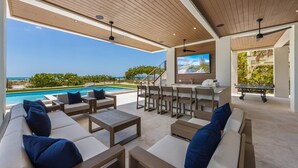 A modern outdoor lounge area with a pool, seating, and a bar. - True Beachfront!  2 Beachfront Masters - Best Location!! (Anna Maria Island)