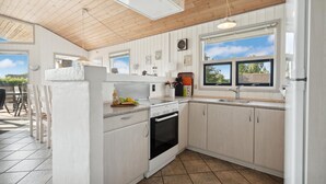 Una cocina moderna con armarios blancos, horno empotrado y un ventanal con vistas al exterior.