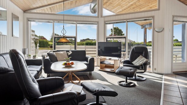 Una sala de estar moderna con un sofá, sillones, una mesa de centro y un televisor.
