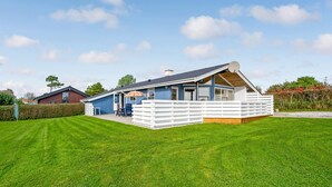 Una casa moderna con techo inclinado, terraza amurallada y césped cuidado.