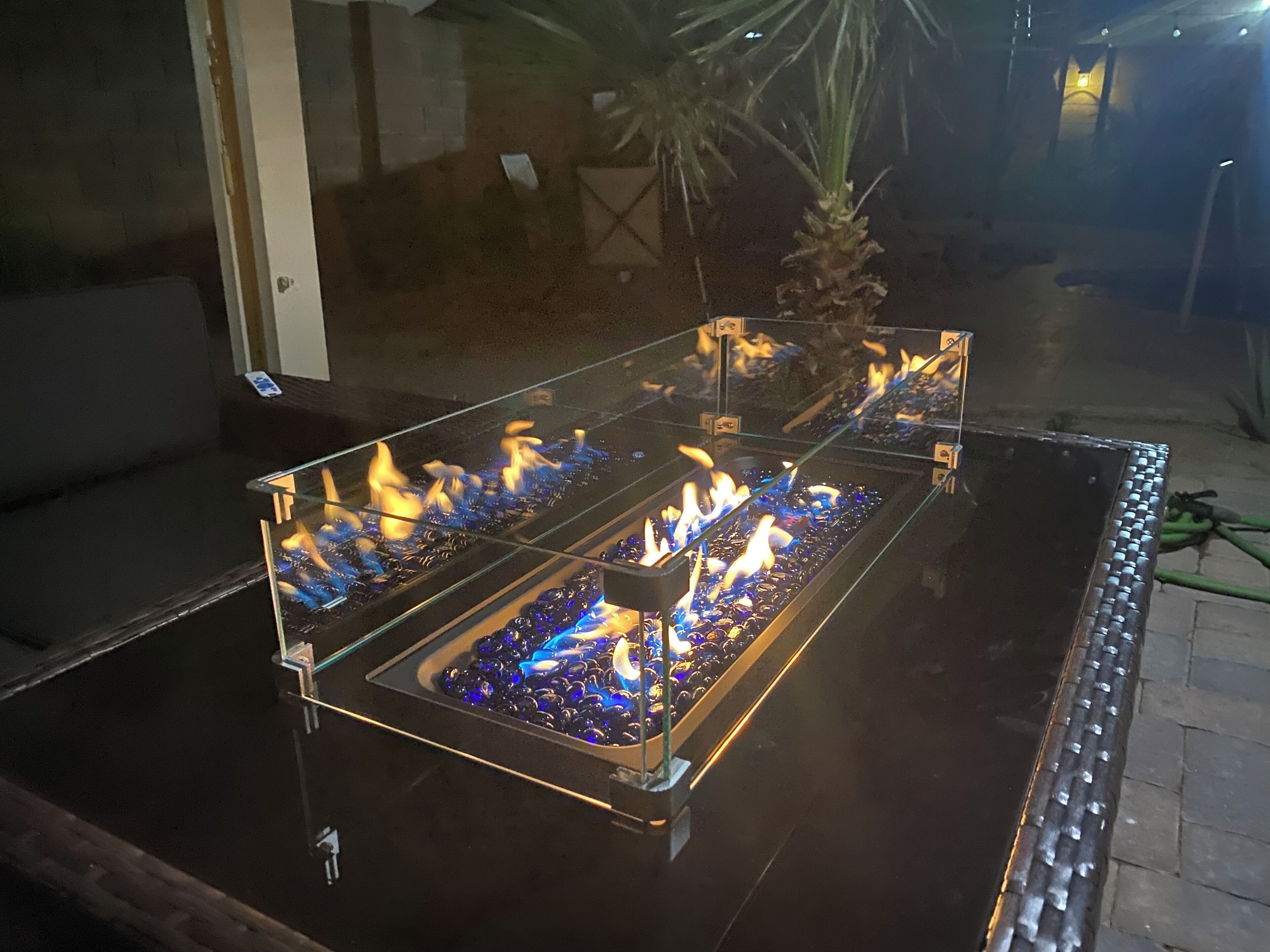 A glass-top outdoor fire feature with multiple burners.