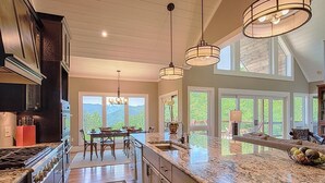 A spacious kitchen with granite countertops, a large island, and a dining area with a view of the outdoors.