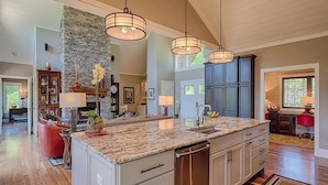 A spacious kitchen with granite countertops, stainless steel appliances, and pendant lighting.