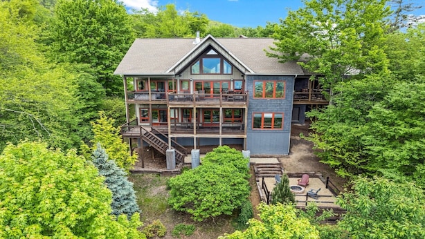 A multi-story house with a balcony, surrounded by dense greenery.