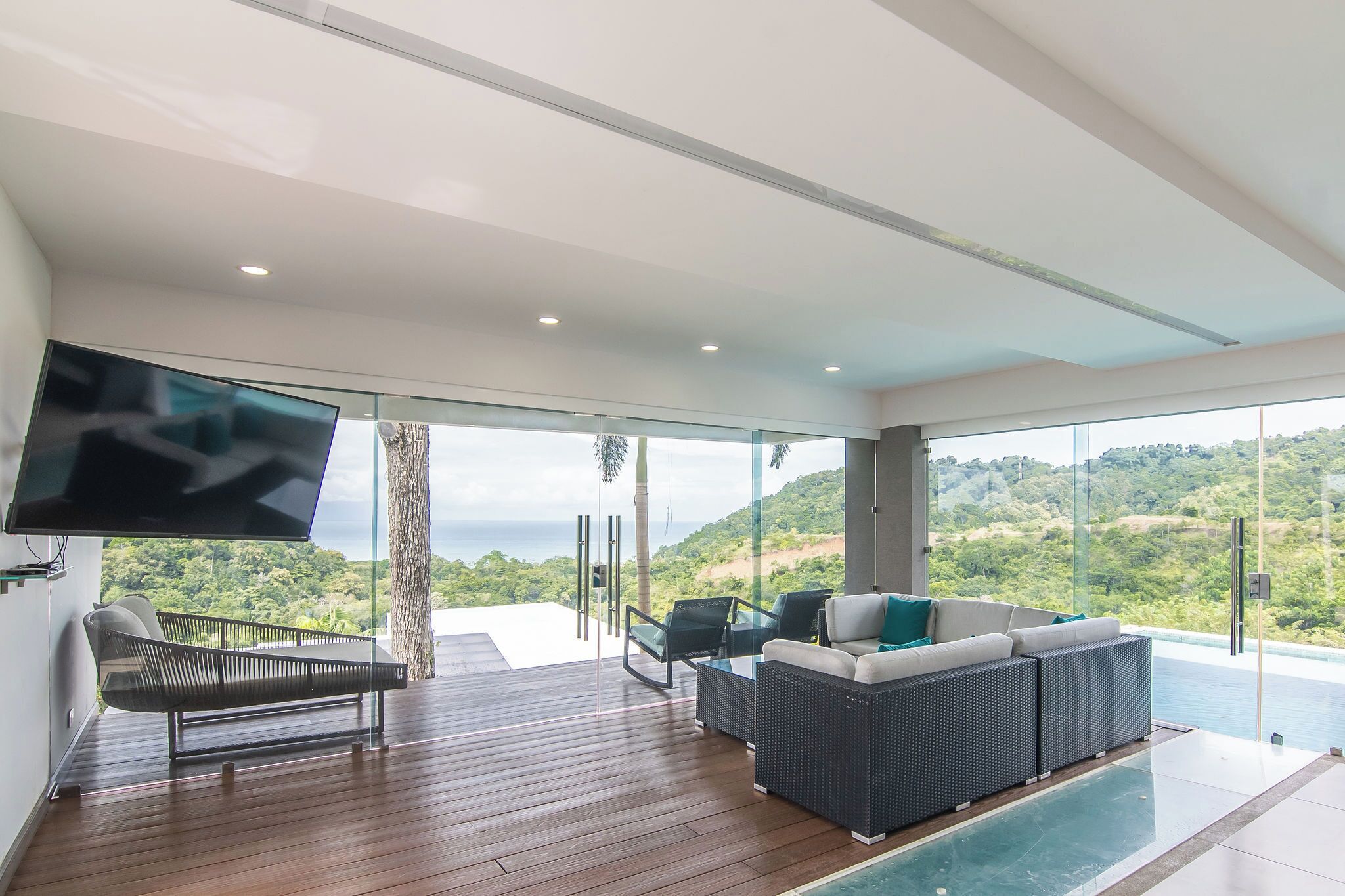 Una sala de estar moderna con un televisor grande, asientos cómodos y vistas a un paisaje exuberante.