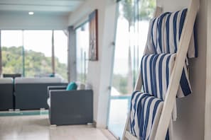 A modern interior with a seating area, large windows, and a view of greenery.