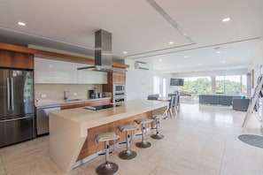 A modern kitchen with a central island, stainless steel appliances, and a bar area with stools.