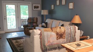 A cozy living room with a white couch, a wooden coffee table, and a rug. There is a door with glass panels leading to a balcony. - Mountain Time in Pigeon Forge Close to Dollywood (Pigeon Forge)