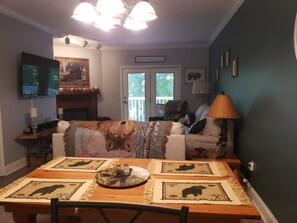 A cozy living room with a fireplace, a television, and a dining area with a table set for two.