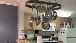 A kitchen with a central island, stainless steel pots, a microwave, and a refrigerator with animal decals. - Mountain Time in Pigeon Forge Close to Dollywood (Pigeon Forge)