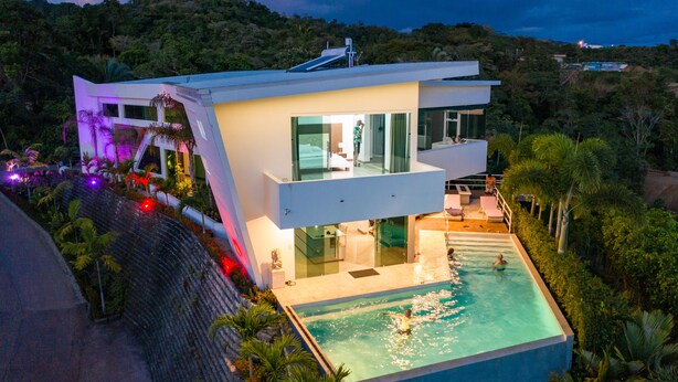A modern house with a swimming pool, large windows, and a balcony overlooking the pool. - Luxury 4BR Ocean View with Infinity Pool & Jacuzzi (Playa Hermosa)