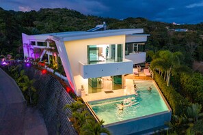 Una casa moderna con piscina, ventanas amplias y un balcón con vistas a la piscina.