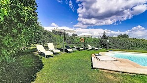 A poolside area with lounge chairs, umbrellas, and a lifebuoy. - La Quercia by Interhome (Orte)