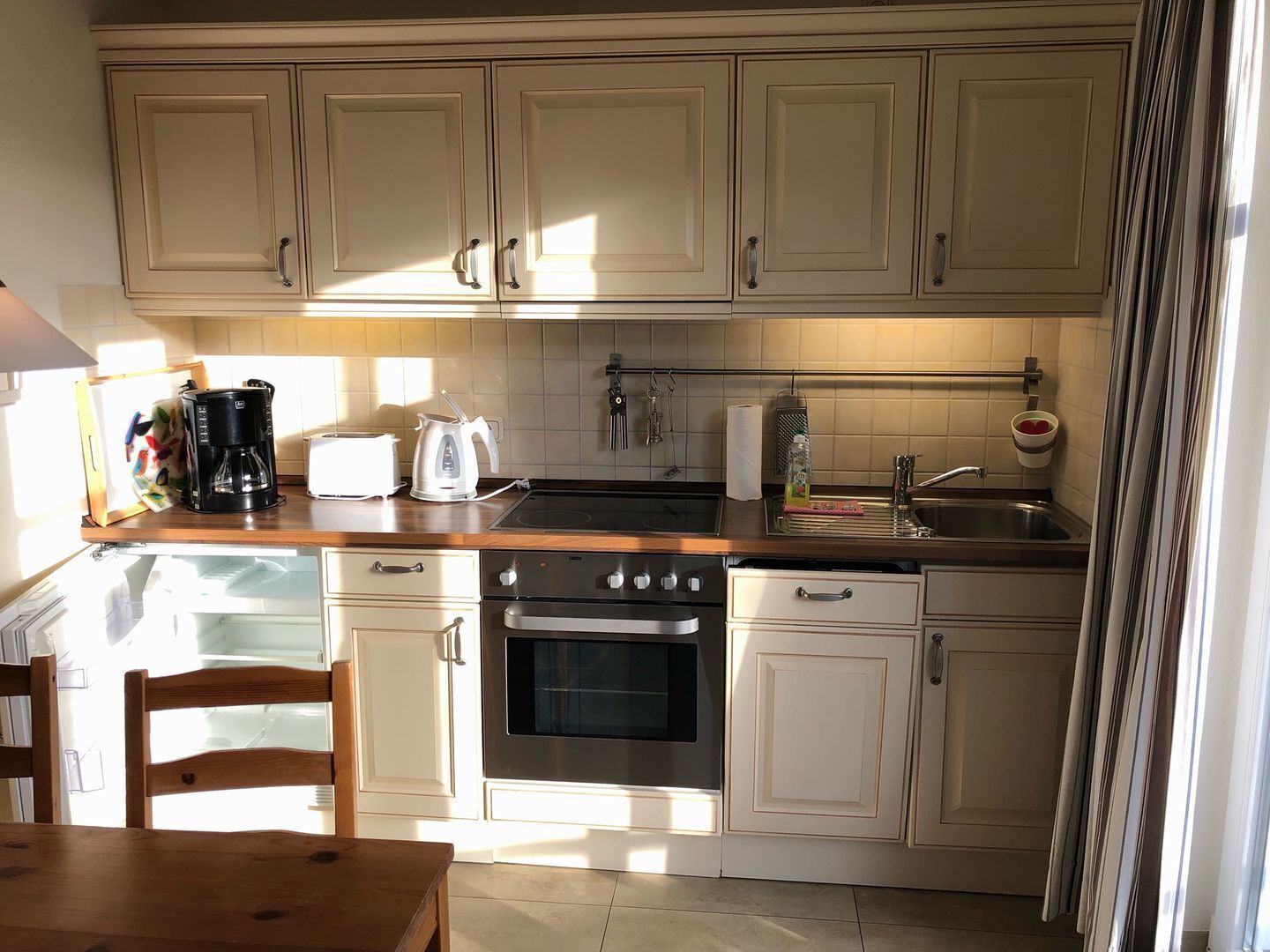 A kitchen with white cabinets, a black stove, a sink, and a wooden dining table.