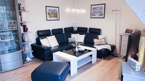 Ein modernes Wohnzimmer mit einer Eckcouch, einem Couchtisch und einer Glastauschablage.