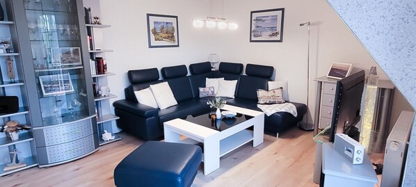 A modern living room with a sectional sofa, a coffee table, and a glass display cabinet.