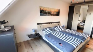 Ein Schlafzimmer mit Bett, Nachttisch, Lampe und einem Wandbild.