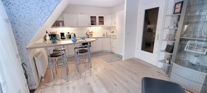 A modern kitchen with white cabinets, a bar area with stools, and a glass display cabinet.
