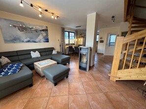 A living room with a sofa, ottoman, and a fireplace. - New row 11a "Haus Ankalath" - modern vacation home for the family (Zingst)