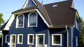 Ein zweistöckiges Haus mit Satteldach, vielen Fenstern und einer kleinen Veranda.
