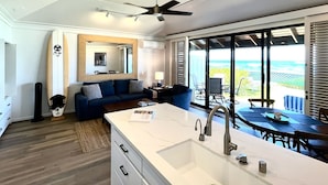 A modern kitchen with a large island, a dining area with a view, and a ceiling fan. - Kiahuna Plantation #198 - The Best Beachfront Condominium on Kauai (Koloa)