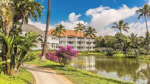 A resort with a pool, surrounded by lush greenery and palm trees. - Kiahuna Plantation #198 - The Best Beachfront Condominium on Kauai (Koloa)