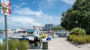 A marina with boats docked, a small building with an American flag, and a 'Rent a Boat Here' sign. - 4BR Private Pool Home, Screened Lanai, & 3mi to SRQ Airport (Sarasota)