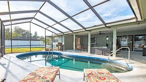 An indoor swimming pool with a glass ceiling, lounge chairs, and a patio area with outdoor furniture. - 4BR Private Pool Home, Screened Lanai, & 3mi to SRQ Airport (Sarasota)