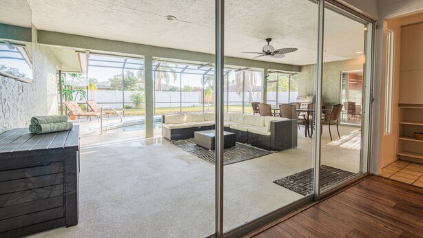 A modern living room with a glass door leading to a patio area. - 4BR Private Pool Home, Screened Lanai, & 3mi to SRQ Airport (Sarasota)