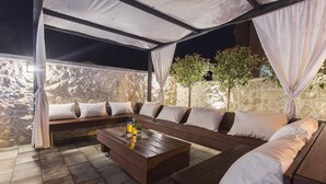 An outdoor seating area with a stone wall backdrop, a wooden bench, and a coffee table.