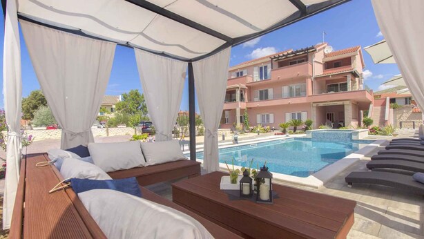 A poolside lounge area with wooden loungers and a pool in the background.