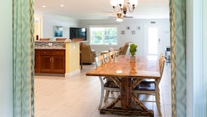 A spacious dining area with a wooden table and chairs, a kitchen in the background, and a ceiling fan. - Blue Haven Retreat Spacious 3BR, 2BA Escape (Sebastian)