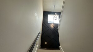 A staircase with a handrail, leading to a room with a black wall and a window. - Modern New 3bd/3.5ba Close To Everything! (Jeffersonville)