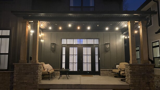 A covered outdoor area with stone steps leading to a door, two cushioned seating areas, and a stone fireplace. - Modern New 3bd/3.5ba Close To Everything! (Jeffersonville)