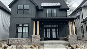 A two-story house with a dark gray exterior, a stone foundation, and a front porch with columns. - Modern New 3bd/3.5ba Close To Everything! (Jeffersonville)